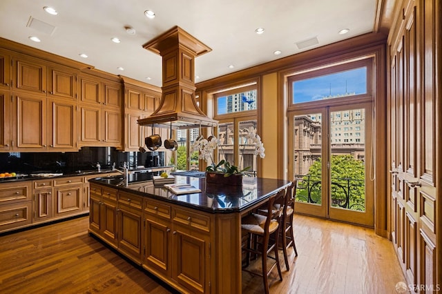 kitchen featuring decorative backsplash, wood-type flooring, a center island, and a healthy amount of sunlight