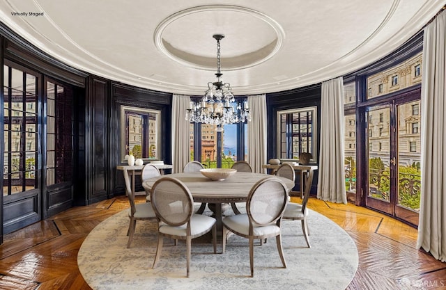 dining area with a raised ceiling, french doors, a chandelier, and parquet flooring