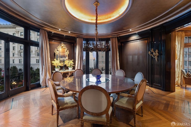 dining area with light parquet flooring, a tray ceiling, and ornamental molding