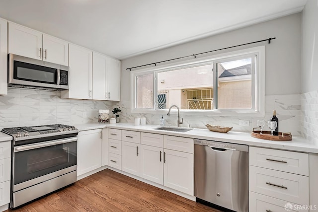kitchen featuring stainless steel appliances, a sink, white cabinets, and light countertops