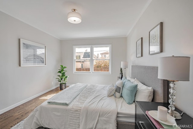 bedroom featuring wood finished floors, ornamental molding, and baseboards