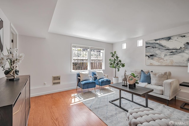 living area with light wood-style floors, baseboards, and heating unit