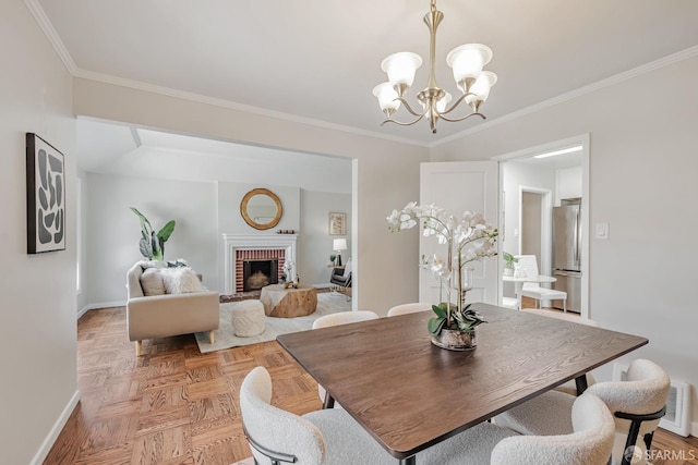 dining room with baseboards, a chandelier, crown molding, and a brick fireplace