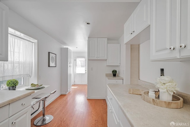 kitchen featuring light countertops, white cabinetry, light wood-style flooring, and baseboards