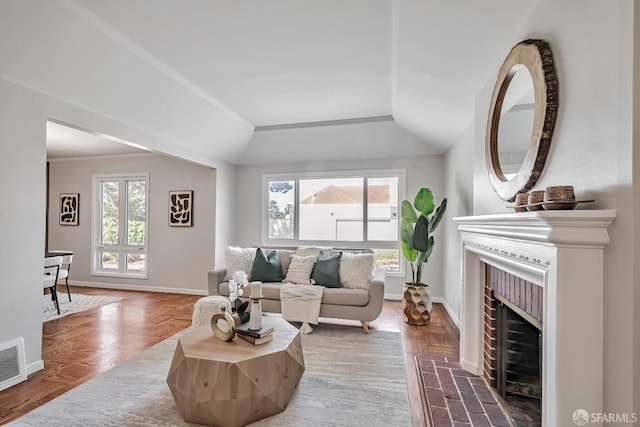 living room featuring baseboards, a brick fireplace, and lofted ceiling