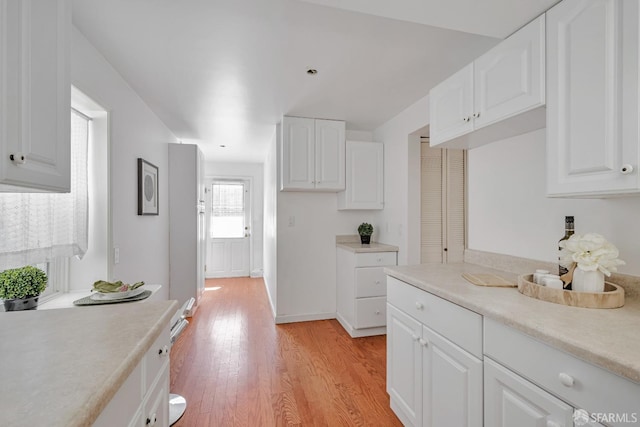 kitchen with light countertops, light wood-style floors, white cabinetry, and baseboards