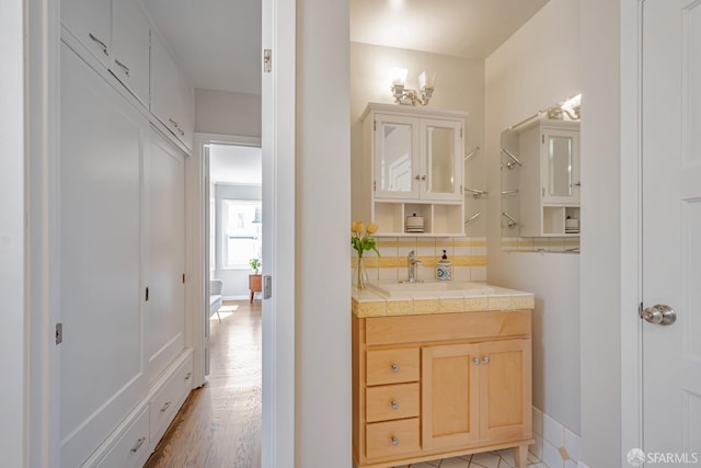 bathroom featuring tasteful backsplash, vanity, baseboards, and wood finished floors