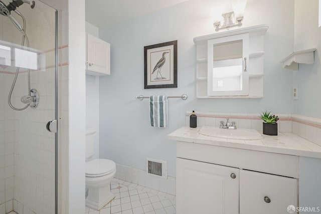 bathroom featuring a shower stall, vanity, tile patterned floors, and toilet