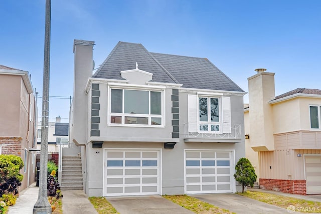 townhome / multi-family property with a garage, stucco siding, driveway, and a chimney