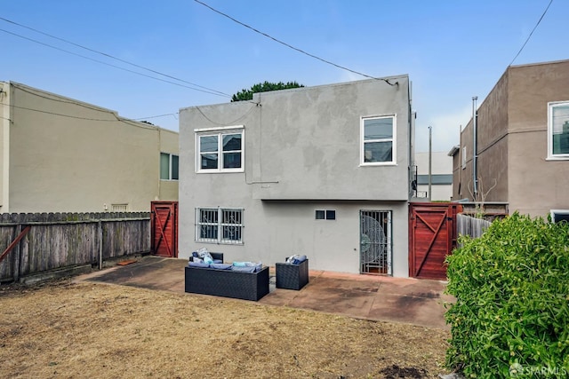 back of property featuring a fenced backyard, outdoor lounge area, a patio, stucco siding, and a gate