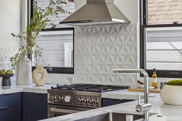 kitchen featuring high end stove, decorative backsplash, island range hood, light stone counters, and plenty of natural light