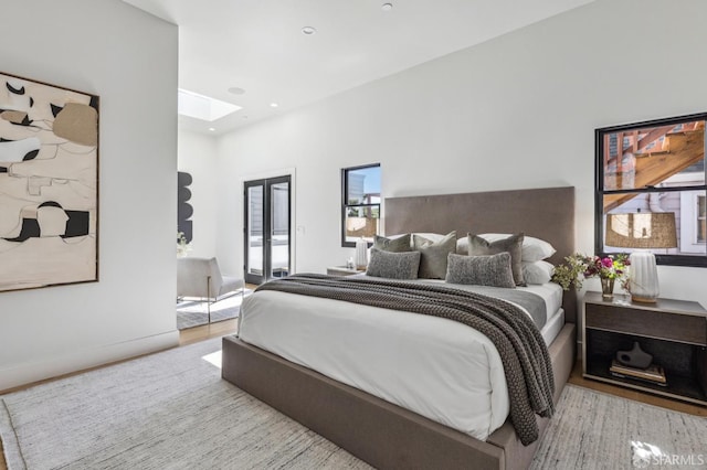 bedroom with a skylight, french doors, and light hardwood / wood-style floors