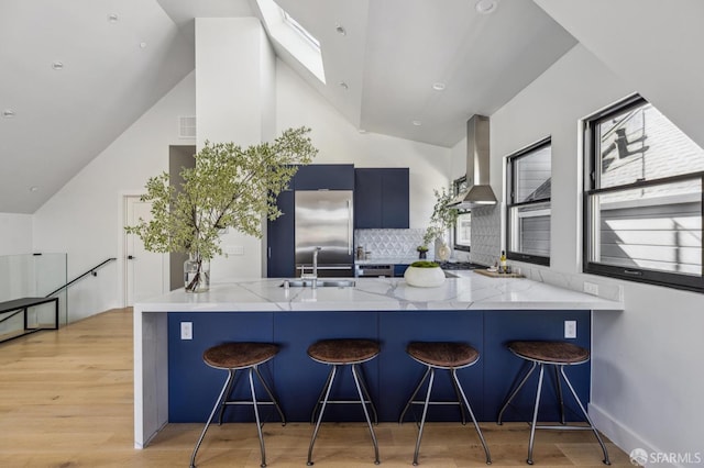 kitchen with kitchen peninsula, wall chimney exhaust hood, and a kitchen breakfast bar