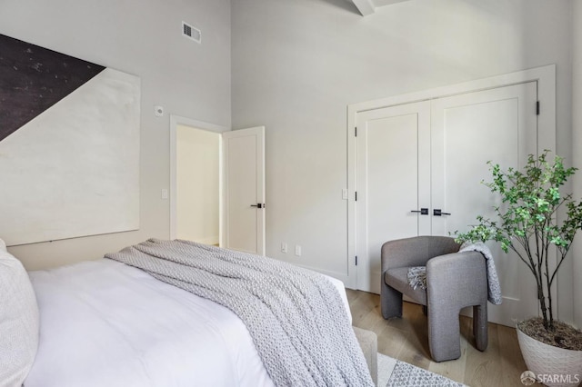 bedroom featuring a closet, a towering ceiling, and light wood-type flooring