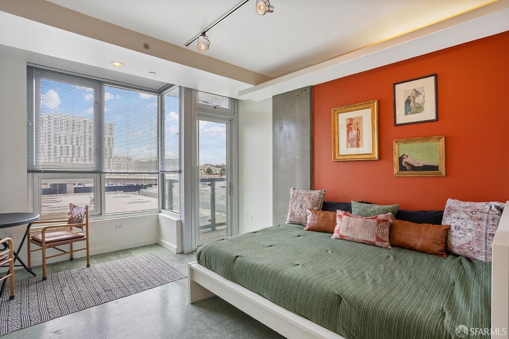 bedroom with concrete floors, access to exterior, baseboards, and track lighting