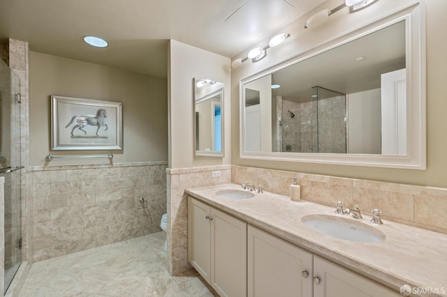 bathroom with a sink, tile walls, a stall shower, and double vanity