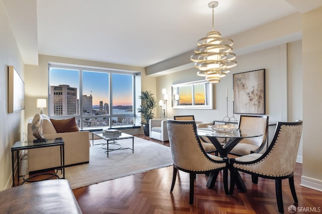 dining area featuring a view of city, a notable chandelier, and baseboards