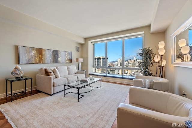 living room with visible vents, baseboards, a city view, and wood finished floors