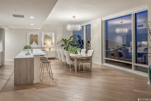 dining space featuring a notable chandelier and light wood-type flooring