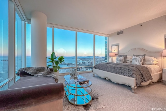 bedroom with expansive windows, a water view, and carpet