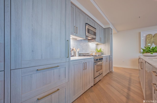 kitchen featuring appliances with stainless steel finishes, light wood-type flooring, and tasteful backsplash