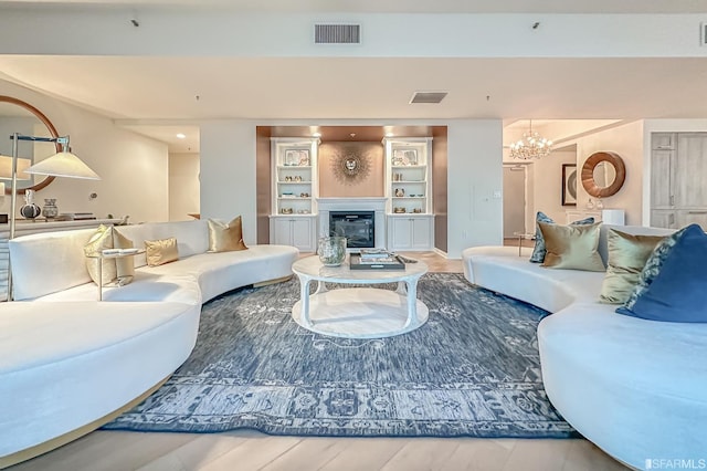 living room featuring an inviting chandelier, hardwood / wood-style floors, and built in features