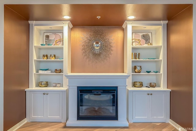 interior space with white cabinets, built in shelves, and light hardwood / wood-style floors