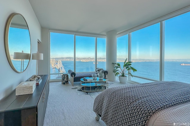 carpeted bedroom featuring a water view, multiple windows, and a wall of windows