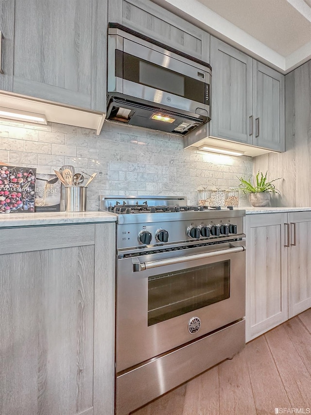 kitchen with light hardwood / wood-style flooring, stainless steel appliances, and tasteful backsplash