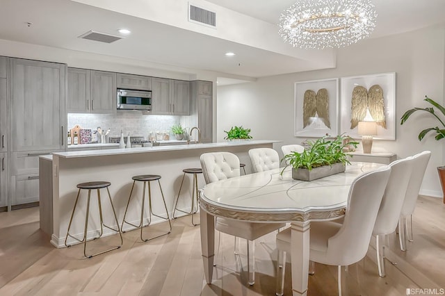 dining room with sink, light hardwood / wood-style flooring, and an inviting chandelier