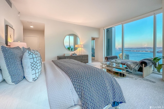 bedroom featuring multiple windows, carpet floors, and a water view