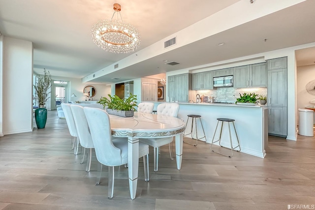 dining space with light hardwood / wood-style floors and a notable chandelier