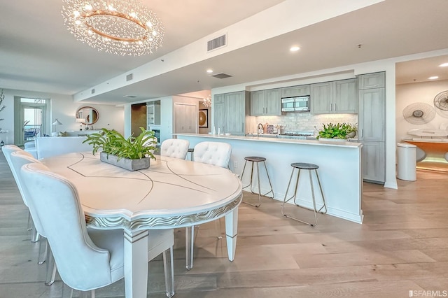 dining space with light hardwood / wood-style floors, a chandelier, and sink