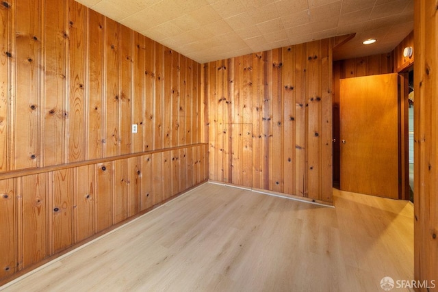 unfurnished room with light wood-style flooring and wooden walls