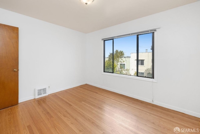 empty room with light wood-type flooring, visible vents, and baseboards