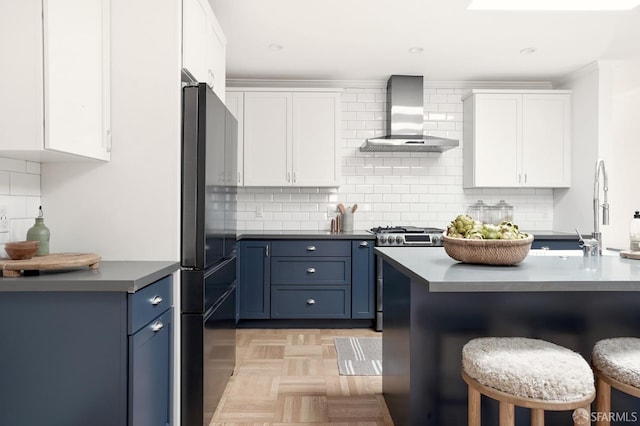 1643 43rd Ave, San Francisco, CA 94122 - kitchen featuring wall chimney range hood, freestanding refrigerator, a kitchen breakfast bar, white cabinetry, and ornamental molding