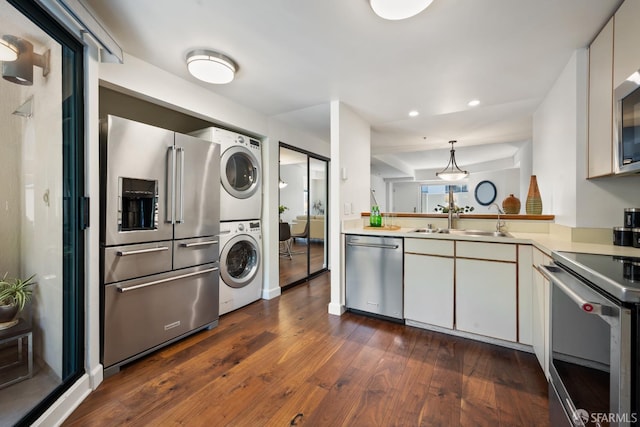 601 Van Ness Ave Unit 35, San Francisco, CA 94102 - kitchen featuring appliances with stainless steel finishes, stacked washing machine and dryer, light countertops, dark wood-style floors, and recessed lighting