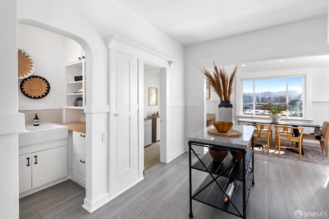 dining space with arched walkways, a mountain view, and light wood-style floors