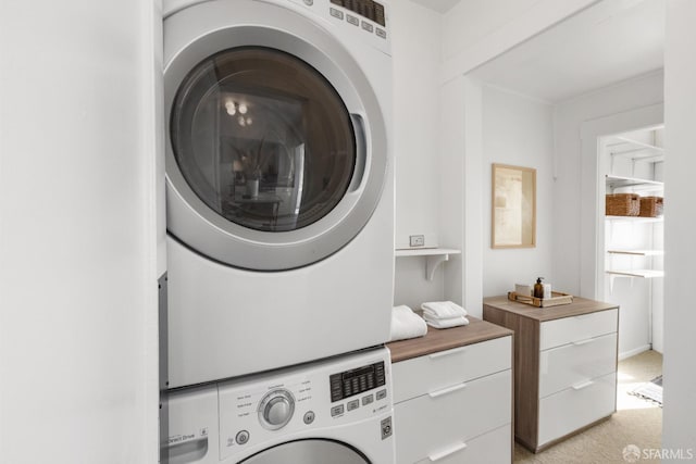 washroom featuring light carpet, stacked washer and dryer, and cabinet space