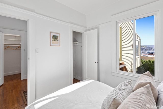 bedroom with a spacious closet, visible vents, and wood finished floors