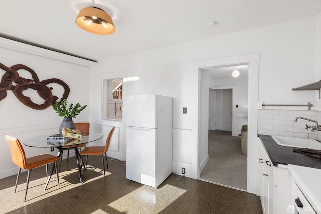 kitchen with freestanding refrigerator, a sink, decorative backsplash, white cabinets, and dark countertops