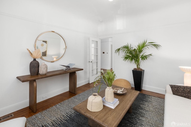 living area with visible vents, baseboards, and wood finished floors