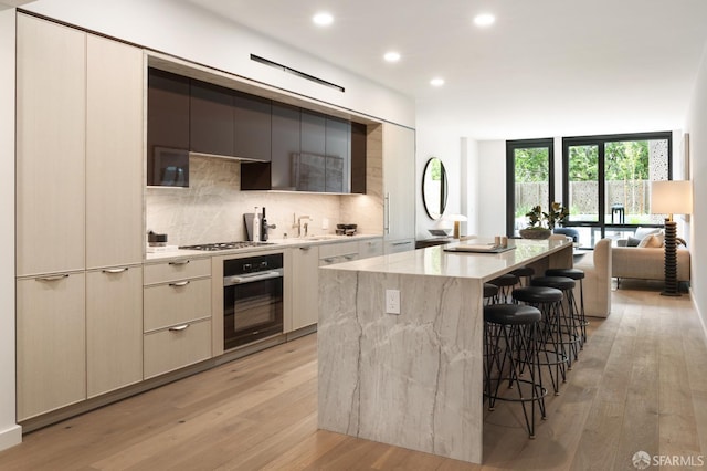 kitchen with appliances with stainless steel finishes, a center island, light hardwood / wood-style flooring, and backsplash