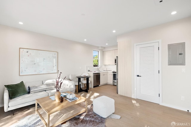 living area featuring electric panel, light wood-style floors, and recessed lighting