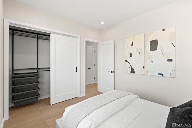 bedroom with wood finished floors, a closet, recessed lighting, and baseboards