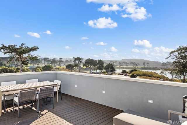 wooden terrace featuring a water view and outdoor dining space