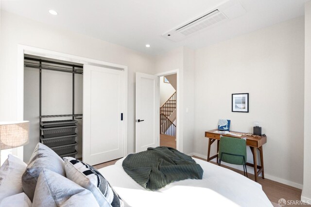 bedroom with wood finished floors, baseboards, a closet, and recessed lighting