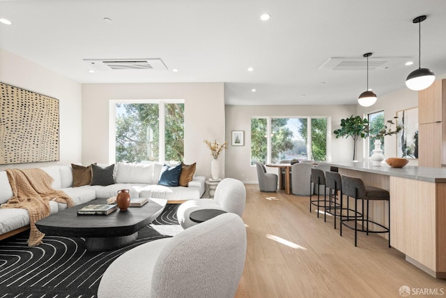 living area with light wood-type flooring, plenty of natural light, and recessed lighting