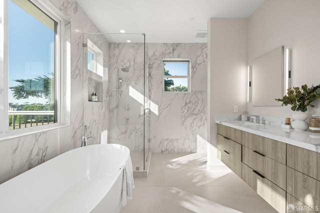 bathroom with a marble finish shower, a soaking tub, vanity, and tile walls