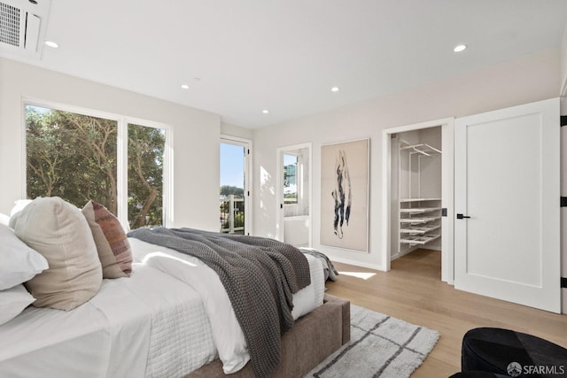 bedroom with light wood-style flooring, recessed lighting, a spacious closet, connected bathroom, and access to outside